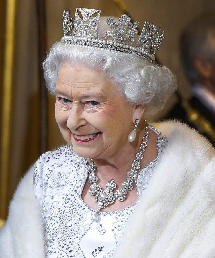 Королева Елизавета II улыбается, покидая Государственное открытие парламента в Палате лордов 8 мая 2013 года в Лондоне, Англия