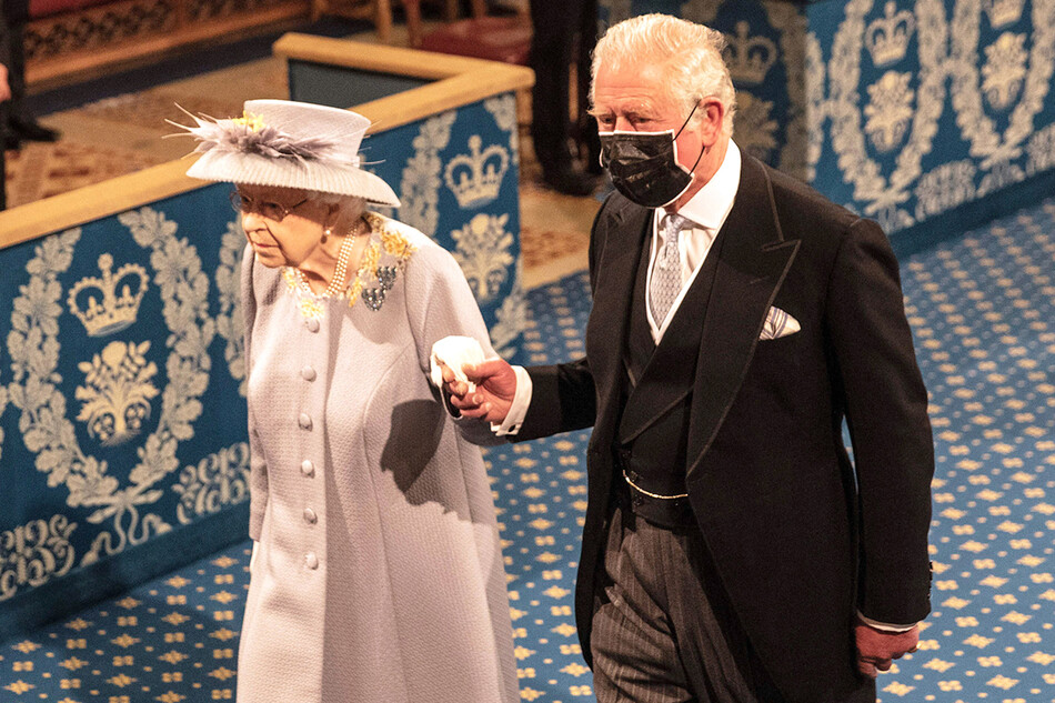 Елизавета II следует за короной имперского государства вдоль королевской галереи в сопровождении принца Чарльза, принца Уэльского, во время государственного открытия парламента в Палате лордов