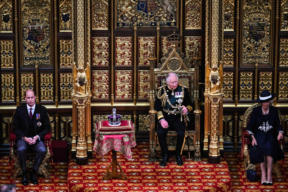 Принц Чарльз, принц Уэльский после прочтения речи королевы, сидит у имперской короны с Камиллой, герцогиней Корнуольской и принцем Уильямом, герцогом Кембриджским в Палате лордов во время государственного открытия парламента в здании парламента в Лондоне, 10 мая 2022 года
