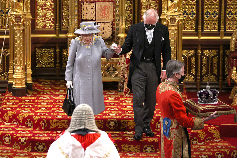 Королева Елизавета II следует за короной имперского государства вдоль королевской галереи в сопровождении принца Чарльза, принца Уэльского, во время государственного открытия парламента в Палате лордов 11 мая 2021 года в Лондоне, Англия