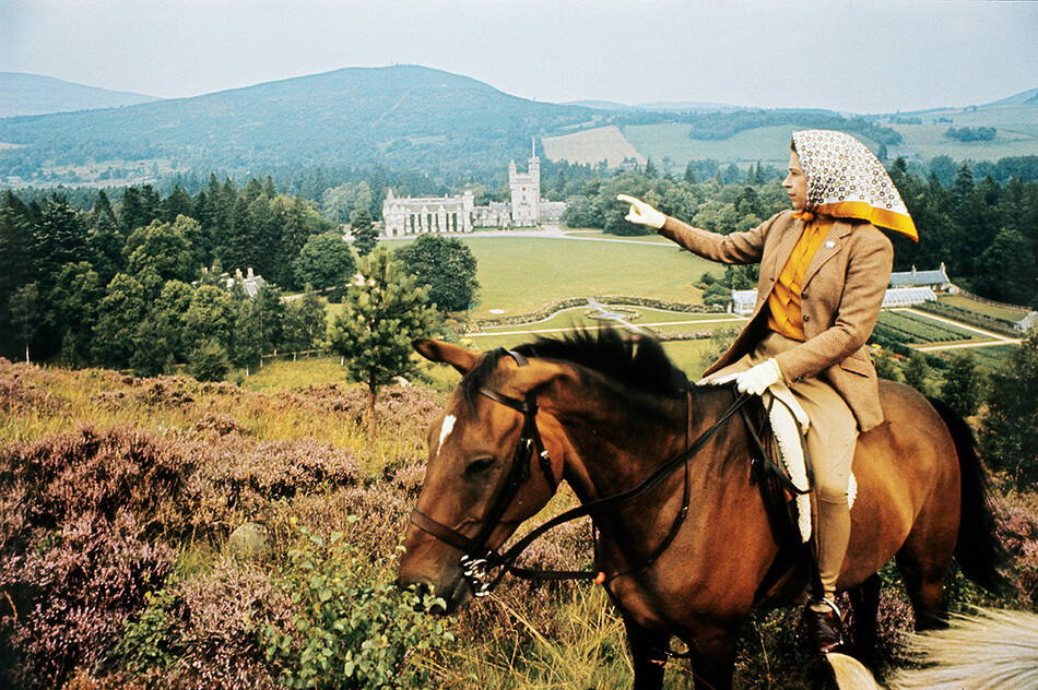 Королева Елизавета II верхом на лошади смотрит на замок Балморал в Шотландии во время ежегодных летних каникул королевской семьи, 1971 г.