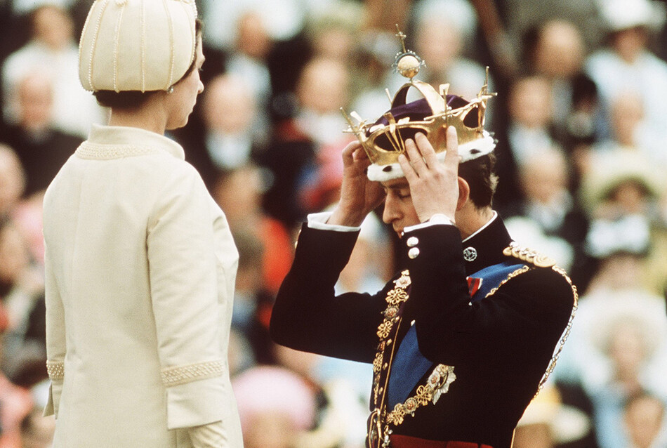 Принц Чарльз преклоняет колени перед королевой Елизаветой II, когда она коронует его принцем Уэльским на инвеституре в замке Кернарвон 1 июля 1969 года в Уэльсе