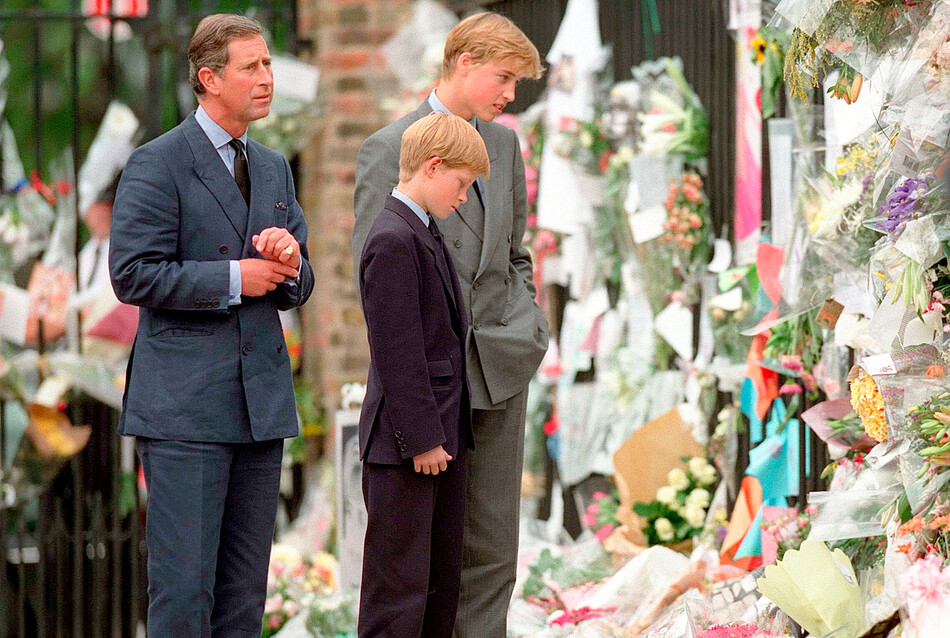 Принц Чарльз с сыновьями принцами Уильямом и Гарри рассматривает цветы, посвящённые принцессе Диане, возле Кенсингтонского дворца 05 сентября 1997 г. в Лондоне, Англия