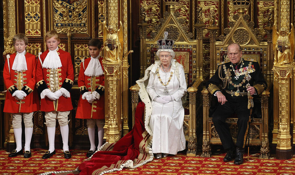 Королева Великобритании Елизавета II (слева) произносит речь королевы с трона в Палате лордов рядом с принцем Филиппом, герцогом Эдинбургским (справа) во время государственного открытия парламента в Вестминстерском дворце в Лондоне, 4 июня 2014 г