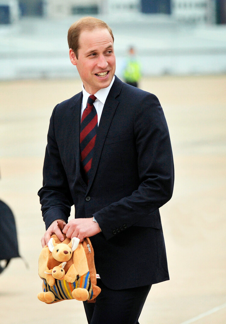 Принц Уильям держит игрушки для принца Джорджа перед посадкой в самолёт на военной базе Фэрбэрн, покидая Австралию в Канберре, 25 апреля 2014