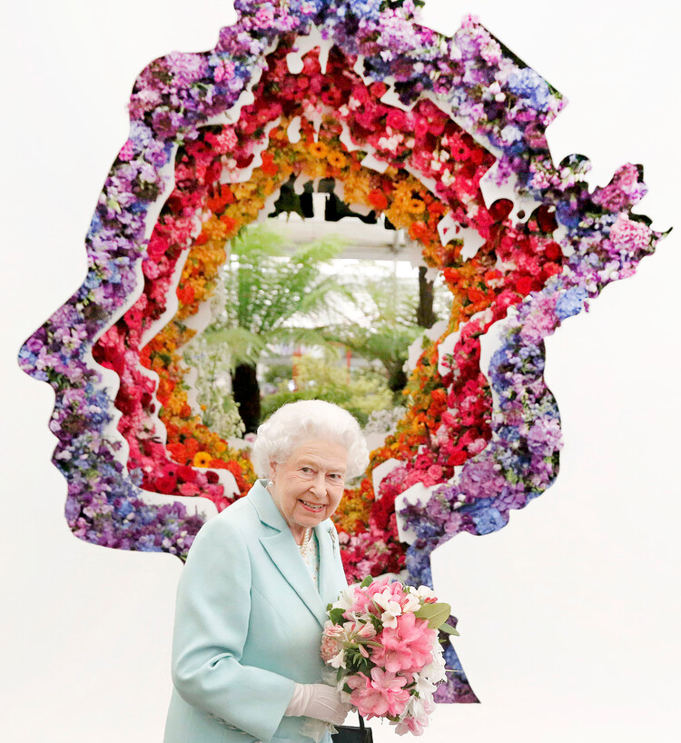 Королева Елизавета II позирует на фоне цветочной композиции во время посещения цветочной выставки Нью-Ковент-Гарден, в Chelsea Flower Show, Королевский госпиталь Челси 23 мая 2016 года в Лондоне, Англия