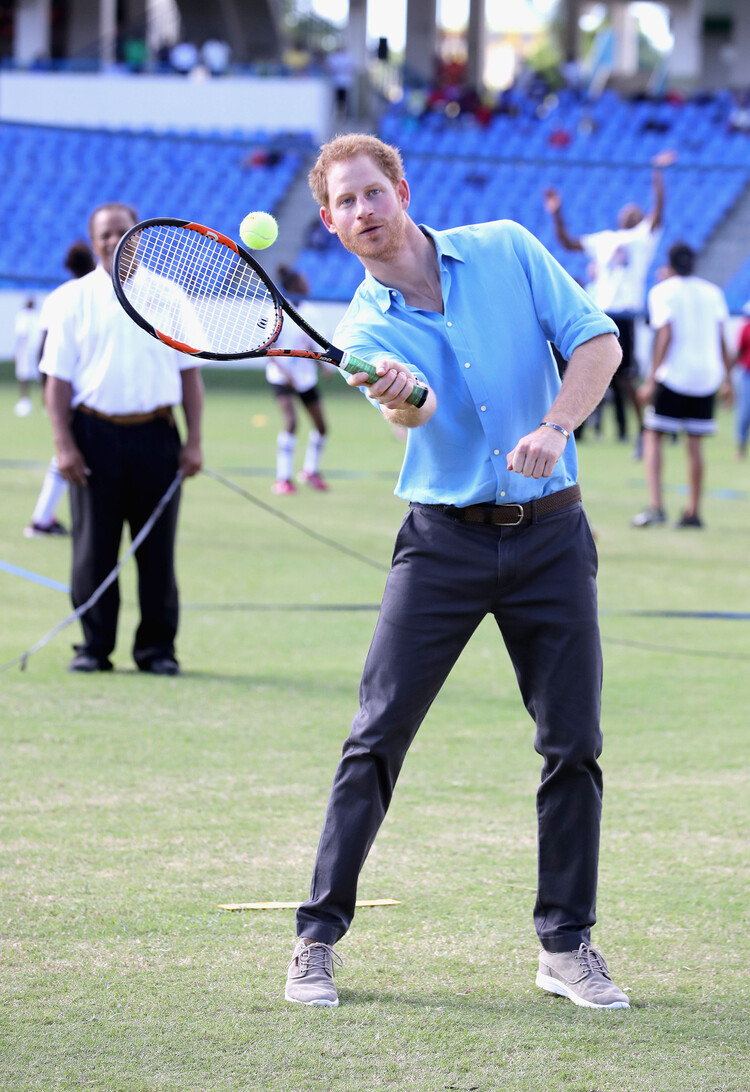 Принц Гарри играет в теннис во время молодежного спортивного фестиваля на стадионе сэра Вивиана Ричардса во второй день официального визита 21 ноября 2016 года в Антигуа, Антигуа и Барбуда