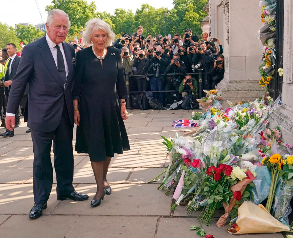 Король Карл III и Камилла, королева-консорт осматривают цветы, возложенные в честь покойной королевы Елизаветы II возле Букингемского дворца 9 сентября 2022 года в Лондоне, Великобритания