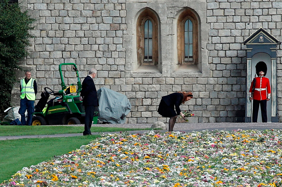 Принц Эндрю наблюдает как Сара Фергюсон собирает цветы, оставленные королевскими поклонниками в дань уважения к королеве Елизавете II ворот Виндзорского замка 16 сентября 2022 г., Англия