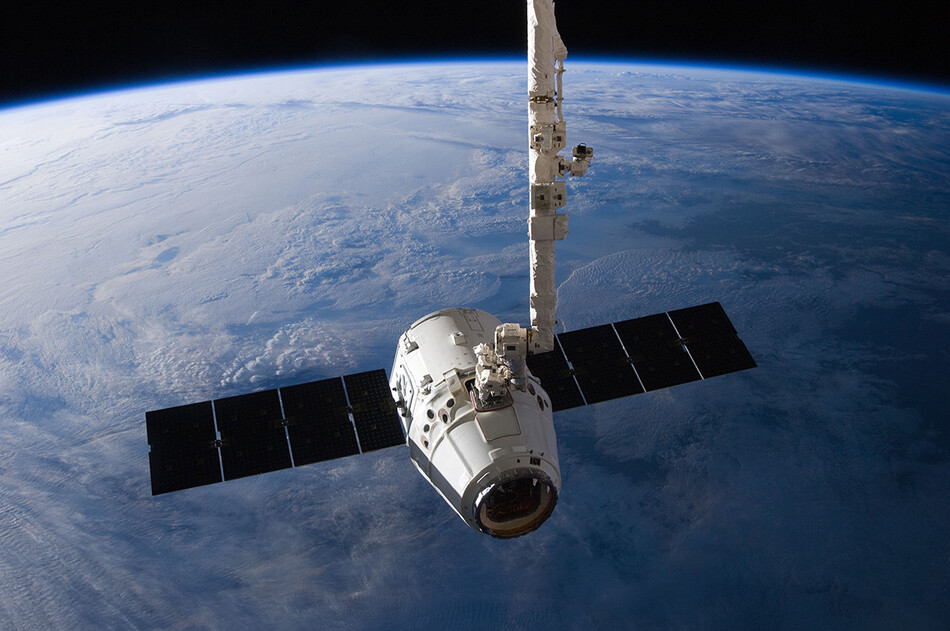 Грузовой корабль SpaceX Dragon изображен незадолго до того, как его выпустила роботизированная рука Международной космической станции Canadarm2, чтобы позволить ему отправиться в сторону приводнения в Тихом океане