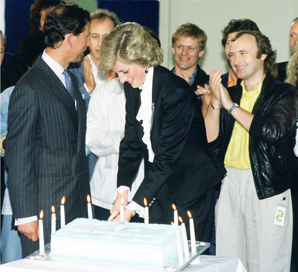 Диана, принцесса Уэльская и принц Чарльз, принц Уэльский разрезают торт во время празднования десятилетия благотворительной организации принца на Уэмбли &laquo;Trust Concert At Wembley&raquo;, певец и музыкант Фил Коллинз стоит слева от Дианы, Лондон, 30 сентября 1982