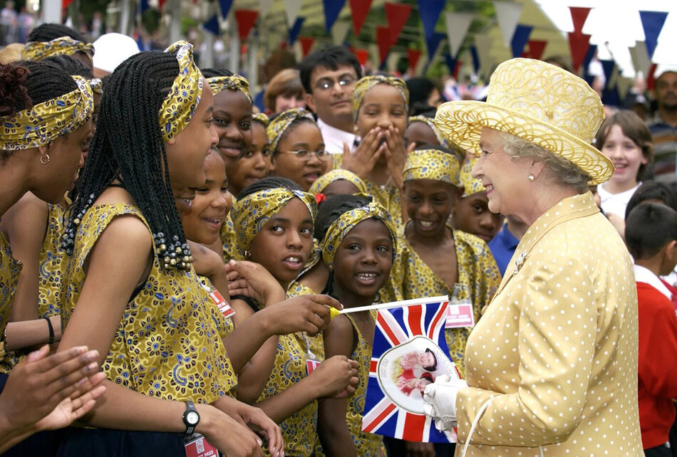 Королева Елизавета II посещает общественный пикник, где местные жители организовали музыкальные и танцевальные представления, чтобы отпраздновать этническое разнообразие Западного Лондона в парке Ганнерсбери, 24 июня 2002 года