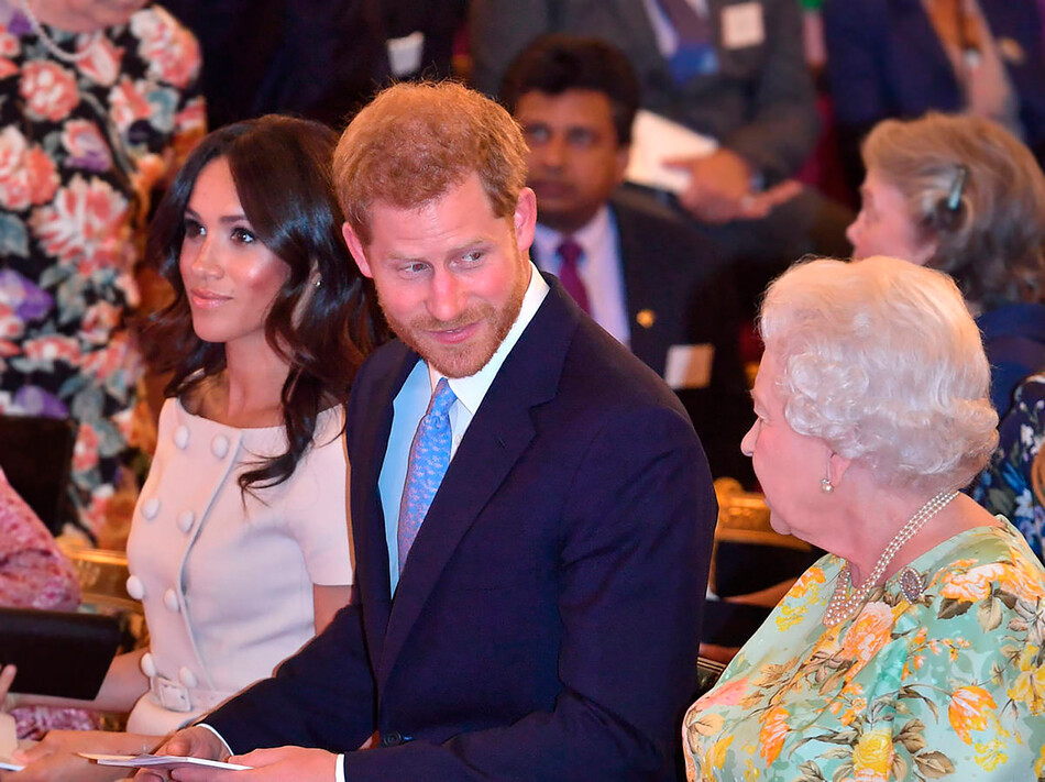Королева Елизавета II с принцем Гарри и Меган Маркл на церемонии награждения молодых лидеров королевы в Букингемском дворце в Лондоне 26 июня 2018б, Англия