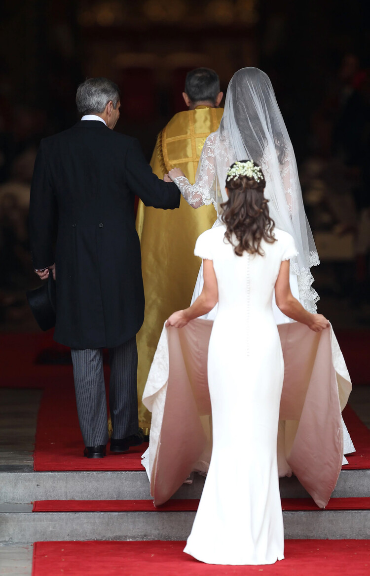 Пиппа Миддлтон помогает сестре Кейт Миддлтон со свадебным платьем в день королевской свадьбы с принца Уильяма в Вестминстерском аббатстве 29 апреля 2011 года. в Лондоне, Англия