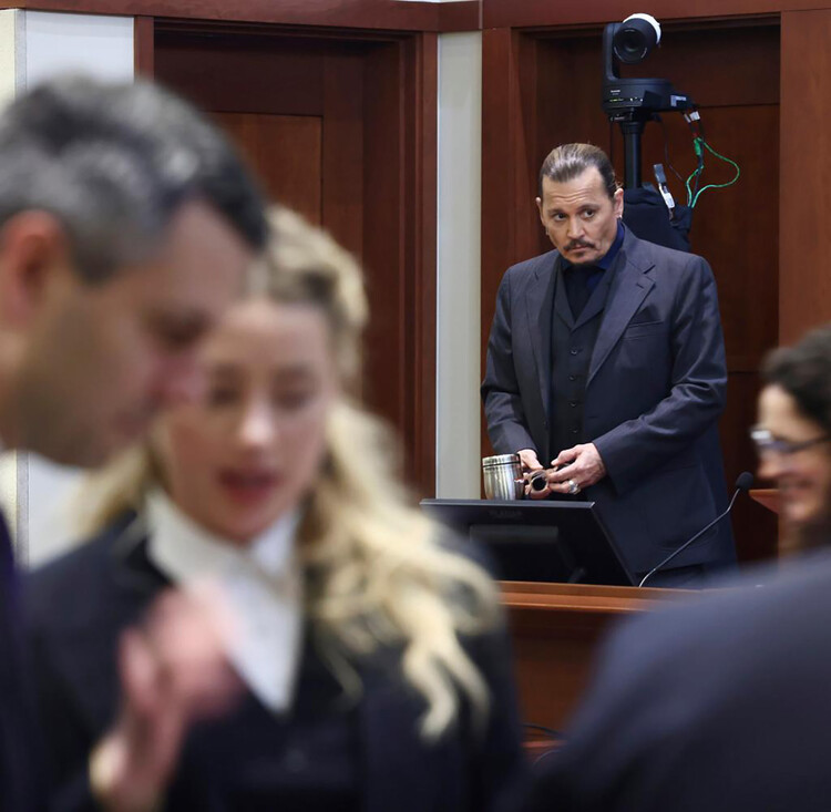 Джонни Депп смотрит как Эмбер Херд общается с адвокатом Беном в зале окружного суда округа Фэрфакс в Фэрфаксе, штат Вирджиния, 26 апреля 2022 года