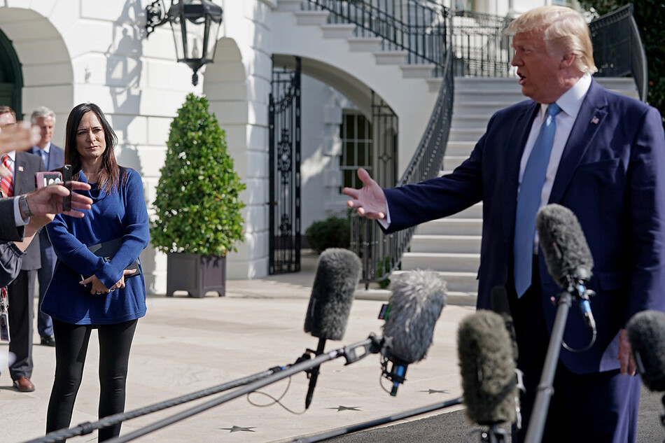 Пресс-секретарь Белого дома Стефани Гришем (слева) наблюдает за тем, как президент США Дональд Трамп разговаривает с журналистами на южной лужайке Белого дома 