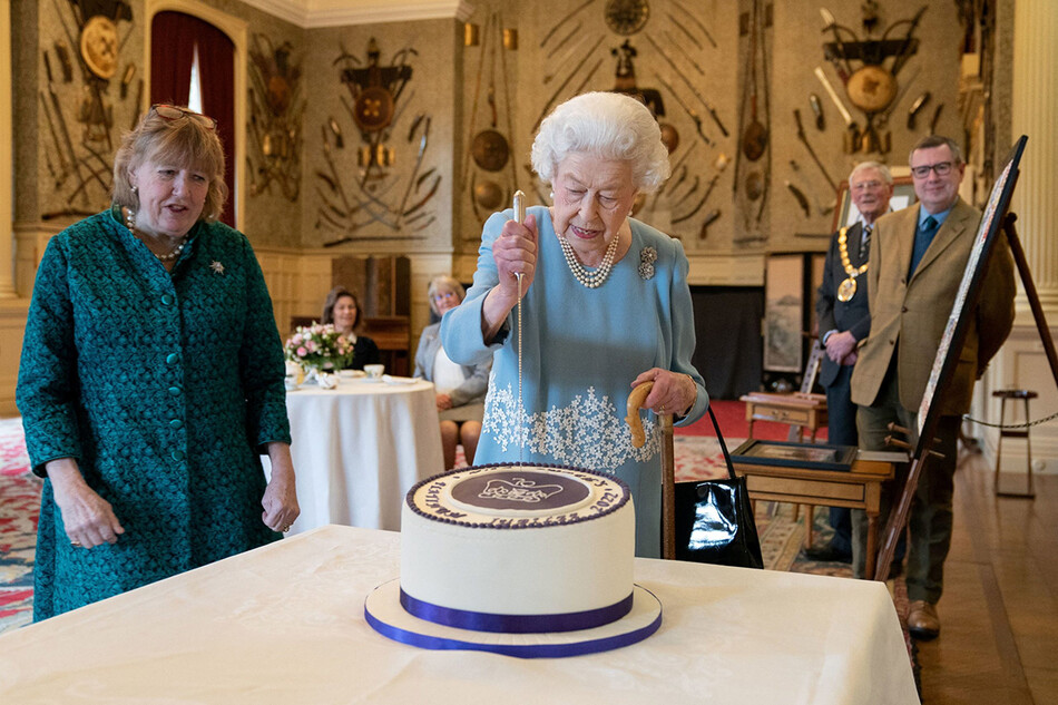 Королева Елизавета II разрезает торт в честь начала платинового юбилея во время приема в бальном зале Сандрингемского дома 5 февраля 2022 года в Кингс-Линн, Англия