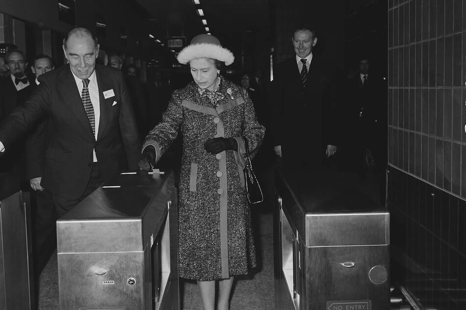 Королева Елизавета II проходит через ворота метро в Центральном аэропорту Хитроу, Лондон, Великобритания, 16 декабря 1977 года