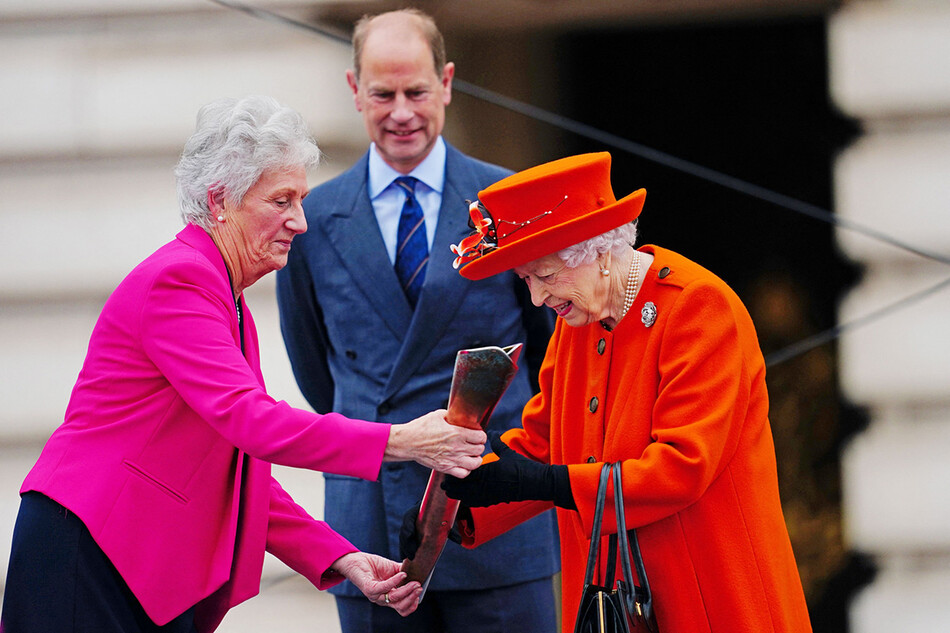 королева Елизавета II (справа) слушает Луизу Ливингстон Мартин, главу Федерации игр Содружества, вместе с принцем Эдуардом, графом Уэссексским, во время запуска эстафеты королевской дубинки в Бирмингеме 2022 года, XXII Игры Содружества на передней территории Букингемского дворца 7 октября 2021 года в Лондоне, Англия