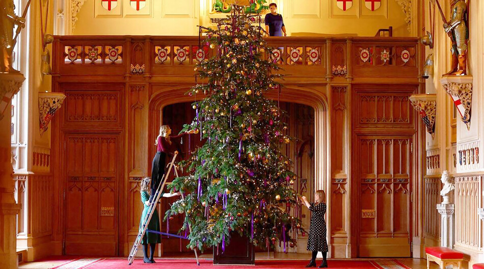 Сотрудники фонда Royal Collection Trust позируют фотографу у недавно установленной рождественской ёлки в Георгиевском зале в Виндзорском замке, 2022г.