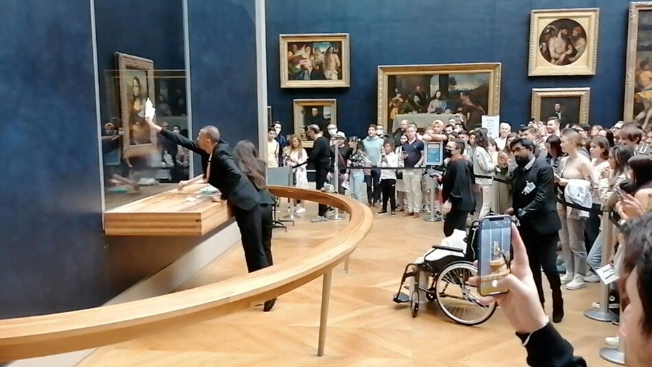 Работник парижского музея, Лувр протирает пуленепробиваемое стекло картины Мона Лиза после нападения злоумышленника с тортом, 30 мая 2022 году, Франция