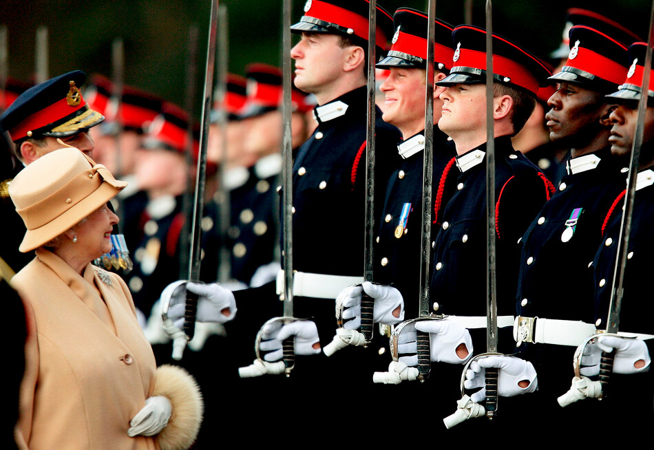 Королева Елизавета II в образе гордой бабушки улыбается принцу Гарри, когда она осматривает солдат на Параде Суверена в военной академии Сандхерст 12 апреля 2006 года в графстве Суррей, Англия