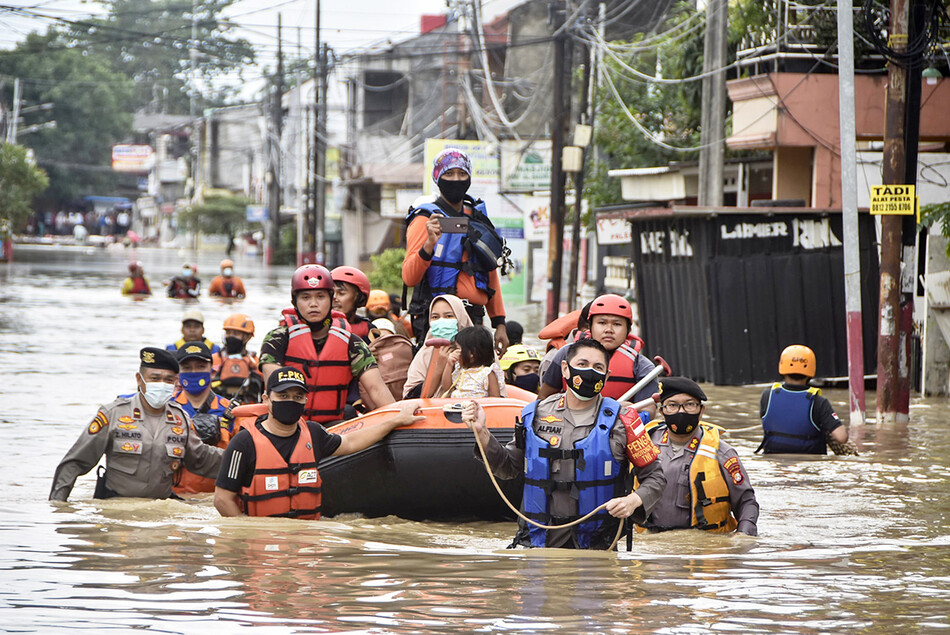 Спасатели эвакуируют жителей из их затопленных домов в Бекаси 19 февраля 2021 года, когда сильный дождь затопил город на окраине Джакарты, Индонезия