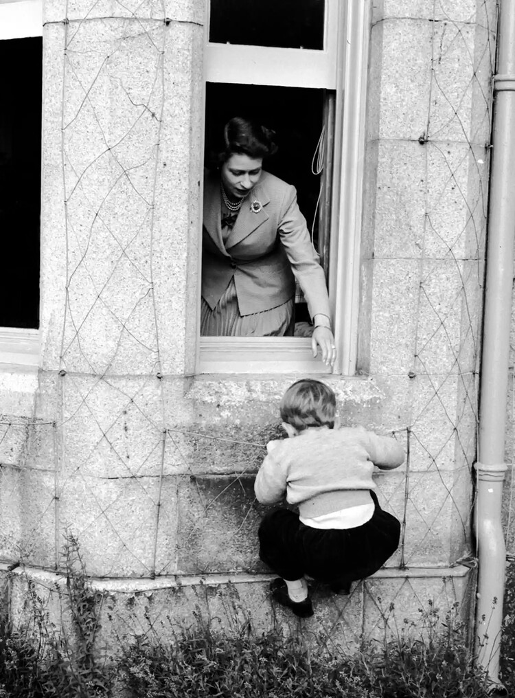 Королева Елизавета II помогает принцу Чарльзу пролезть через окно в замке Балморал, 28 сентября 1952 года, Шотландия