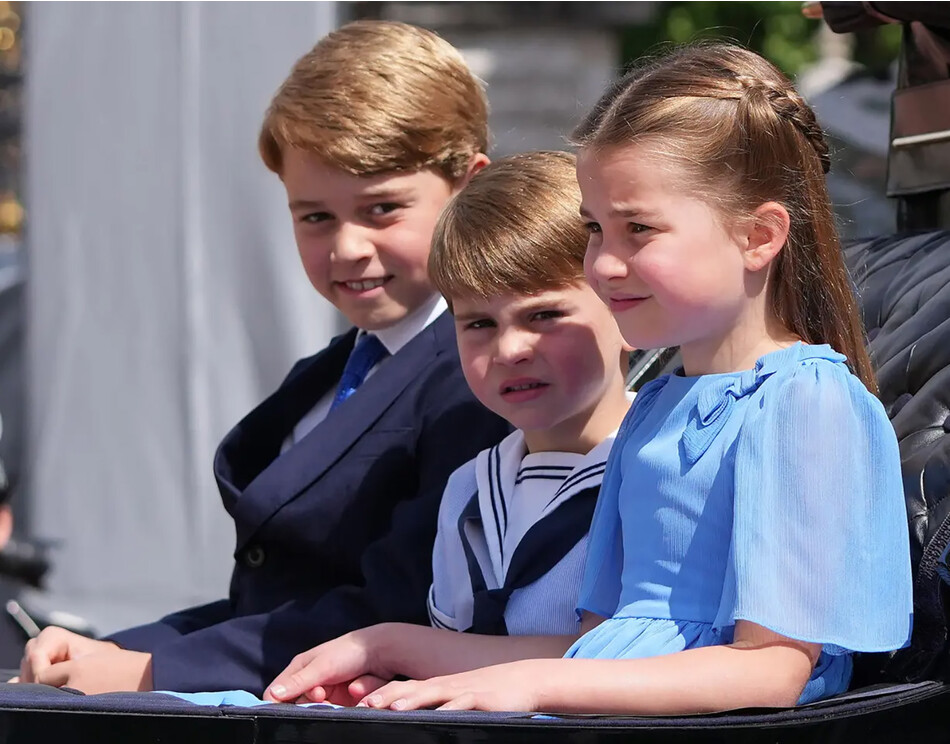 Принцесса Шарлотта взяла руку принца Луи после того, как он активно ей махал, сказав младшему брату прикатить во время поездки со старшим братом принцем Джорджем в карете с открытым верхом на параде Trooping the Colour следуя по маршруту вдоль к Букингемскому дворцу центре, 2 июня 2022 года в Лондоне, Англия