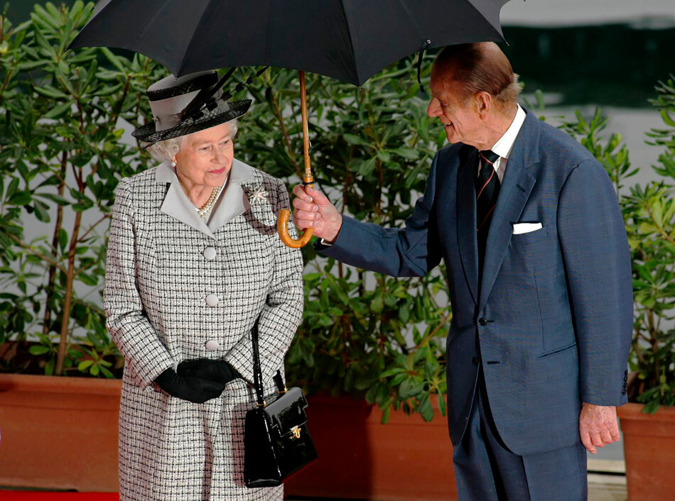 Принц Филипп держит зонтик для жены во время государственного визита королевы Елизаветы II на Мальту 24 ноября 2005 г.