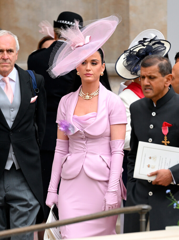 Кэти Перри в нежно-сиреневом костюме, состоящем из юбки-карандаш и приталенного пиджака с короткими рукавами от Vivienne Westwood на коронации Карла III