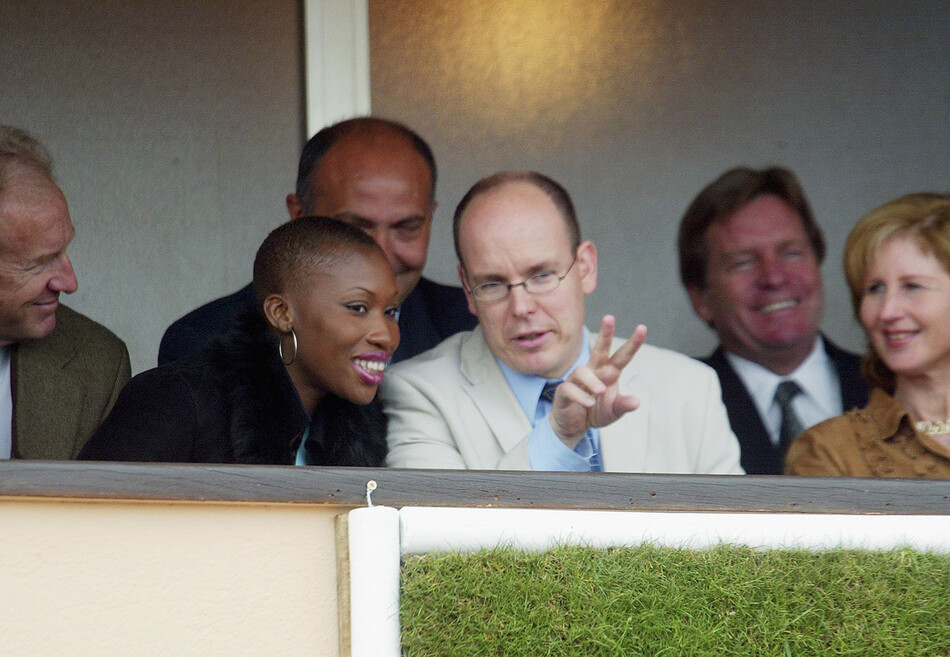 Князь Монако Альбер (в центре) беседует с Николь Кост (слева), пока они смотрят матч из его личной ложи на Monaco Tennis Open в апреле 2002 года в Монако