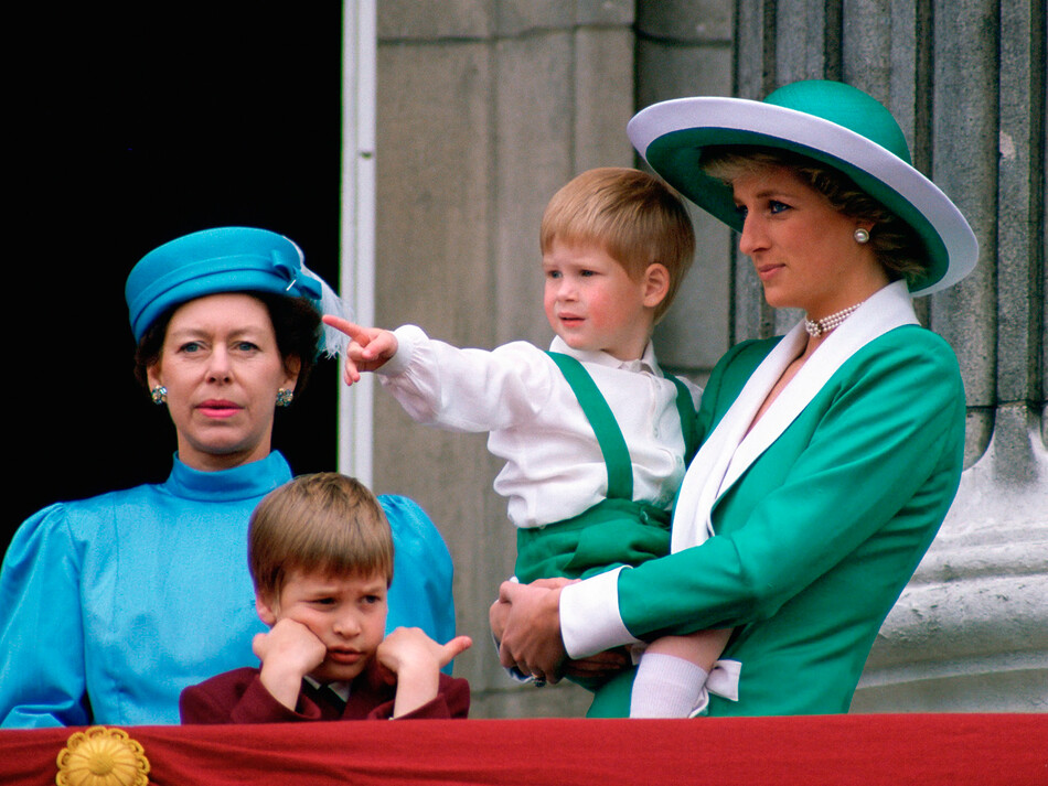 Диана, принцесса Уэльская, держит на руках молодого принца Гарри, наблюдая за тем, как принц Уильям и принцесса Маргарет высаживаются с балкона Букингемского дворца 11 июня 1988 года