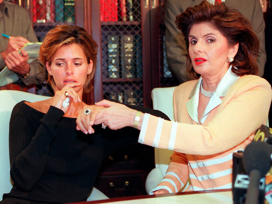 Келли Фишер (слева) и её адвокат Глория Оллред во время пресс-конференции 14 августа 1997 года в Лос-Анджелесе, демонстрируют большое обручальное кольцо с сапфиром и бриллиантами, подаренное ей бывшим женихом Доди Аль-Файедом