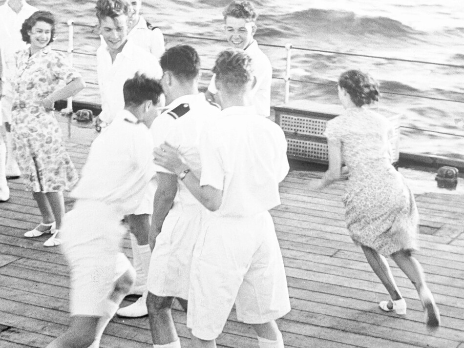 Принцесса Елизавета (вверху слева) и принцесса Маргарет Роуз (в правом углу фотографии), ускользает от гардемарина, играя в пятнашки на борту HMS Vanguard, во время путешествия королевской семьи на борту линкора по пути в Южную Африку, 28 февраля 1947 г.