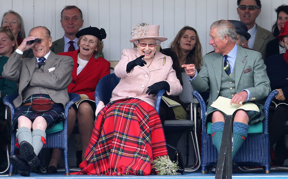 Принц Филипп, герцог Эдинбургский, королева Елизавета II и принц Чарльз, принц Уэльский смеются, наблюдая за гонками в мешках на ежегодных Играх Бремера Хайленд в Мемориальном парке принцессы Королевской и герцога Файфа 7 сентября 2013 года в Бремаре, Шотландия