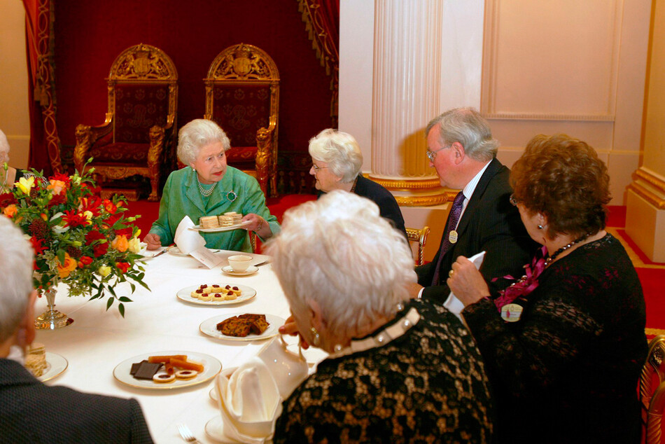 Елизавета II предлагает бутерброды гостям, принимая женскую сухопутную армию и лесозаготовительный корпус в Букингемском дворце, 21 октября 2010