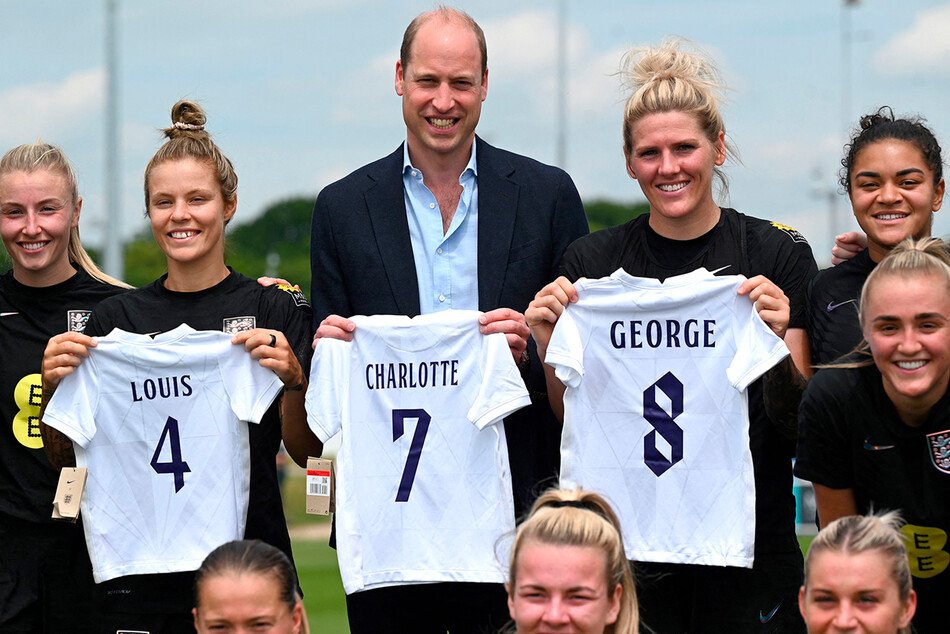 Принц Уильям и игроки женской команды Англии по футболы держат футболки с именами Кембриджских детей: Луи, Джорджа и Шарлотты, 15 июня 2022 года, Лондон