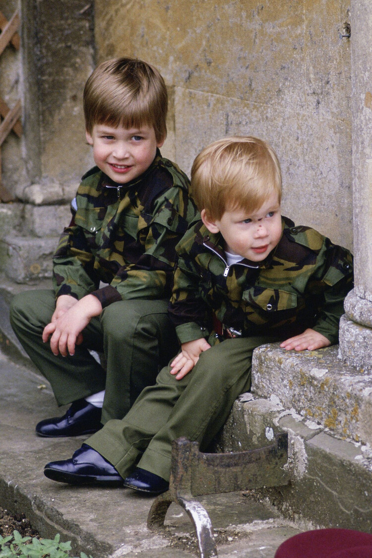 Принц Гарри и принц Уильям сидят вместе на ступенях дома Хайгроув в армейской форме 18 июля 1986 года в Тетбери, Англия