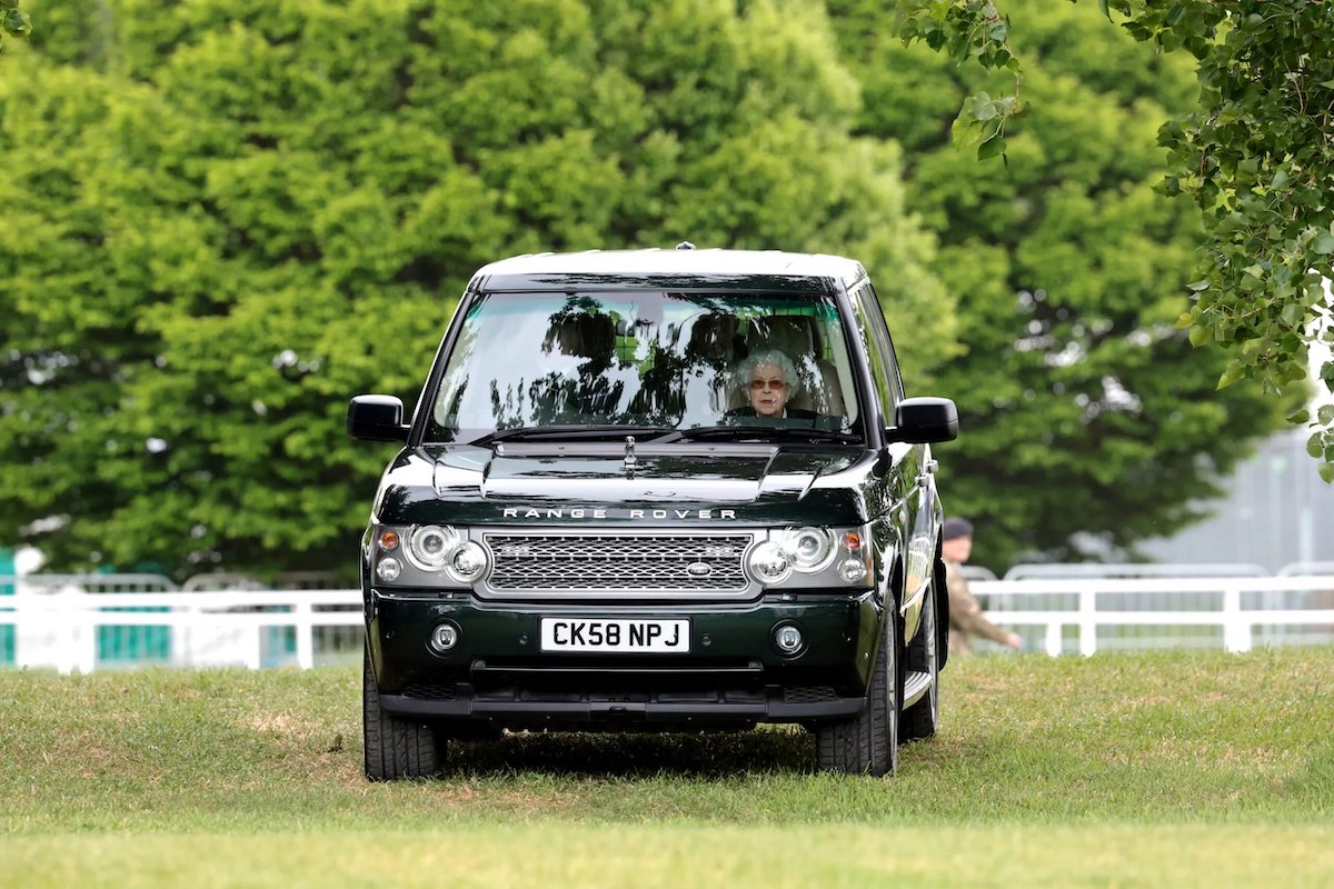 Королева Елизавета II прибывает на своем автомобиле Range Rover, чтобы посмотреть, как её лошадь «Балморал Лея» будет принимать участие в скачках
